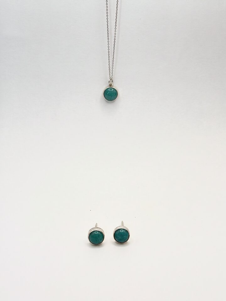 Round teal stone pendant in silver on a fine chain, with matching round teal stud earrings, on a white background.